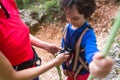 A woman shows a child how to use a carabiner for belaying