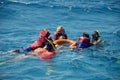 Instructor teaches tourists snorkeling. People are floating on sea, holding on to lifebuoy. Active recreation on Red Sea, resort