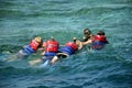 Instructor teaches tourists snorkeling. People are floating on sea, holding on to lifebuoy. Active recreation on Red Sea, resort