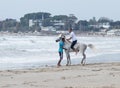 Instructor trains a young man to ride a horse on the shore of the Mediterranean Sea near the city Acre in Israel