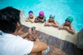 Instructor using stopwatch while training little swimmers at poolside