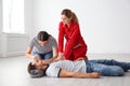 Instructor with woman practicing first aid on unconscious man