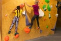 Instructors helping children climb wall in gym