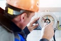 Instrumentation fitter adjusts and diagnoses gauge or pressure gauge at indoor industrial facility. Close-up rear view.