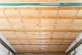 Insulated ceiling of a private house with a wooden crate. The roof is insulated with glass wool and sheathed with a vapor barrier