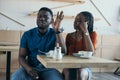 insulted african american man sitting at table with girlfriend