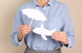 Insurance agent covering paper plane with umbrella cutout on color background, closeup. Travel safety Royalty Free Stock Photo