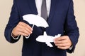 Insurance agent covering paper plane with umbrella cutout on color background, closeup. Royalty Free Stock Photo