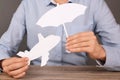 Insurance agent covering paper plane with umbrella cutout at table, closeup. Royalty Free Stock Photo