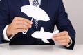 Insurance agent covering paper plane with umbrella cutout at table, closeup. Travel safety