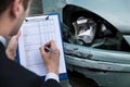 Insurance agent examining car after accident
