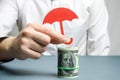 An insurance agent holds a red umbrella over dollar bills. Savings protection. Keeping money safe. Investment and capital Royalty Free Stock Photo