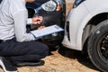 Insurance Agent Inspecting assessed Damaged Car checking and signing on report insurance claim form process after accident