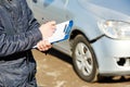 Insurance agent recording car damage on claim form Royalty Free Stock Photo