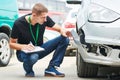 Insurance agent recording car damage on claim form Royalty Free Stock Photo