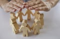 Insurance agent's hands protect wooden figures of people standing in circle in front of him. Royalty Free Stock Photo