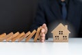 Insurance agents or family leaders are using hands to prevent Dominos from falling into the house. Royalty Free Stock Photo