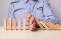 Insurance and business risk management concept. Businessman hand closeup protecting wood blocks from falling. Domino Royalty Free Stock Photo