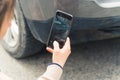 Insurance concept. Outdoor close-up shot of a caucasian woman taking a picture of a front fender after a minor collision Royalty Free Stock Photo