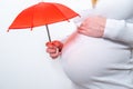 Insurance concept. Small umbrella and insurance policy to pregnant