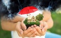 Insurance concept - umbrella demonstrating protection. Family holding house model with green lawn, closeup