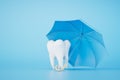 Insurance for dental treatment. tooth under an umbrella on a blue background. 3D render Royalty Free Stock Photo