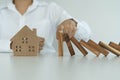 insurance with hands protect a house. The wooden domino block is about to fall on the house. Home insurance or house insurance con Royalty Free Stock Photo