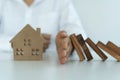 Insurance with hands protect a house. The wooden domino block is about to fall on the house. Home insurance or house insurance Royalty Free Stock Photo