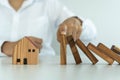Insurance with hands protect a house. The wooden domino block is about to fall on the house. Home insurance or house insurance con Royalty Free Stock Photo