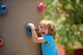 Insurance kids. Portrait of kid boy climbing on practical wall indoor, bouldering training. Health care insurance