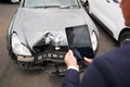 Insurance Loss Adjuster Taking Picture With Digital Tablet Of Damage To Car From Motor Accident Royalty Free Stock Photo