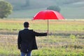 Insurance and protection concept, businessman with umbrella in the field