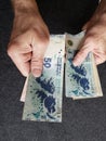 hands of an older man holding argentinean banknotes