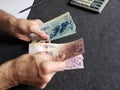 hands of an older man holding argentinean banknotes