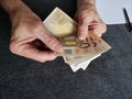 hands of an older man counting european banknotes