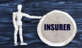 INSURER word on a wooden circle on a dark background with a male figurine