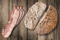 Bacon Rashers And Dark Integral Wholegrain Bread Cut Loaf Set On Old Weathered Coarse Wood Grunge Background Royalty Free Stock Photo