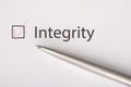 Integrity - checkbox with a tick on white paper with metal pen. Checklist concept