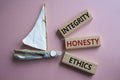 Integrity Honesty Ethics symbol. Concept words Integrity Honesty Ethics on wooden blocks. Beautiful pink background with boat.