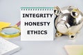 INTEGRITY HONESTY ETHICS A word, a text written on a notebook next to a piggy bank, a magnifying glass, a calculator, stickers Royalty Free Stock Photo