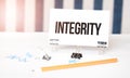 Integrity sign on paper on white desk with office tools. Blue and white background