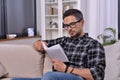 Intellectual mature man with stylish glasses engrossed in captivating book. Amid cozy decor, he relishes tranquil reading session