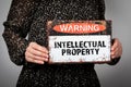 Intellectual Property. Warning sign with text in the hands of a woman Royalty Free Stock Photo