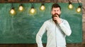 Intellectual task concept. Man with beard and mustache on thoughtful face stand in front of chalkboard. Bearded hipster Royalty Free Stock Photo