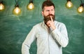 Intellectual task concept. Man with beard and mustache on thoughtful face stand in front of chalkboard. Guy thinking Royalty Free Stock Photo