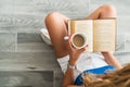 Intellectual young girl sit on floor and drink a cup of coffee, while she is reading a book. Royalty Free Stock Photo