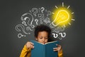 Intelligent black kid student reading book and having idea. Brainstorming and idea concept