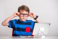 Intelligent boy wearing glasses working on laptop computer. Boy in eyeglasses doing homework Royalty Free Stock Photo