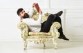 Intelligent concept. Man with beard and mustache sits on armchair and reads book, white wall background. Scientist Royalty Free Stock Photo