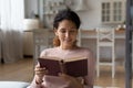 Intelligent hispanic woman read old antiquarian volume of classic literature